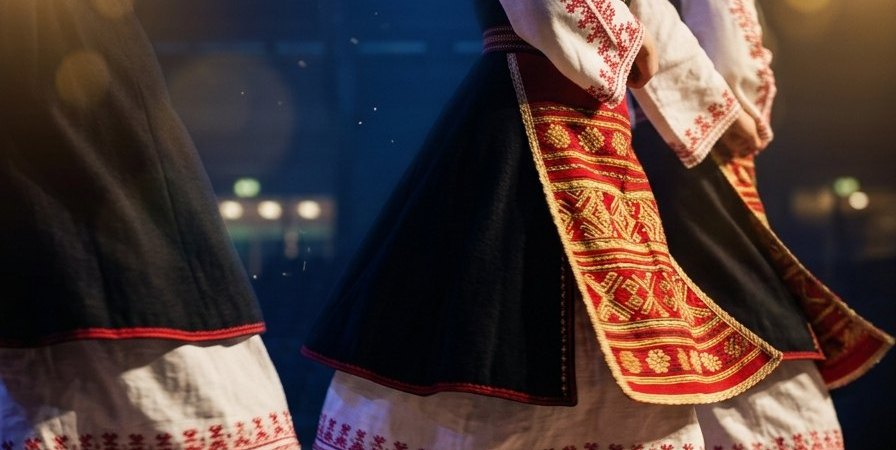 Детайл от българска народна носия — бяла риза с червена шевица, черен сукман и тъкана престилка